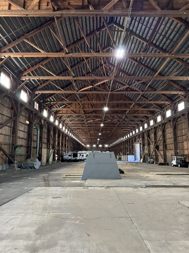 User-provided reference of the long timber hall with exposed roof trusses, high windows and concrete floor